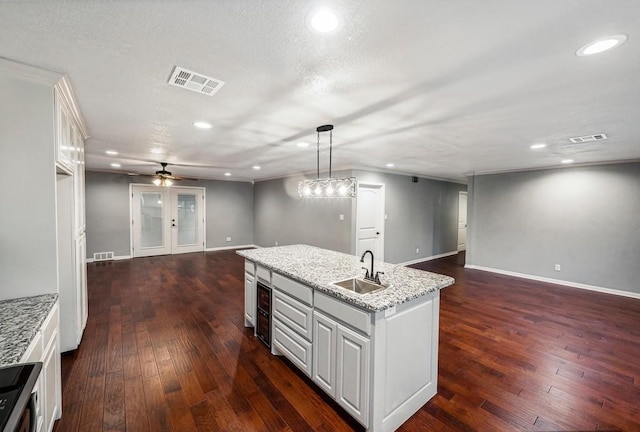 kitchen featuring white cabinetry, sink, dark hardwood / wood-style floors, pendant lighting, and a kitchen island with sink