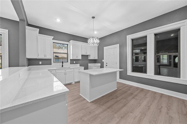 kitchen featuring a center island, sink, light hardwood / wood-style flooring, decorative light fixtures, and white cabinetry