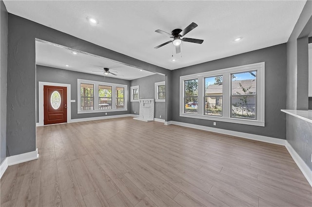 unfurnished living room with light hardwood / wood-style flooring, a wealth of natural light, and ceiling fan