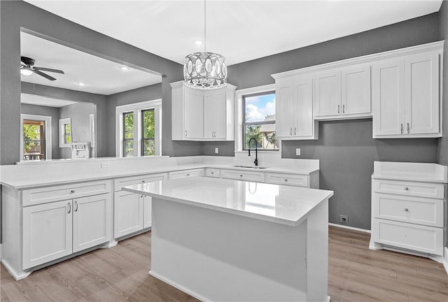 kitchen with kitchen peninsula, a kitchen island, white cabinetry, and sink