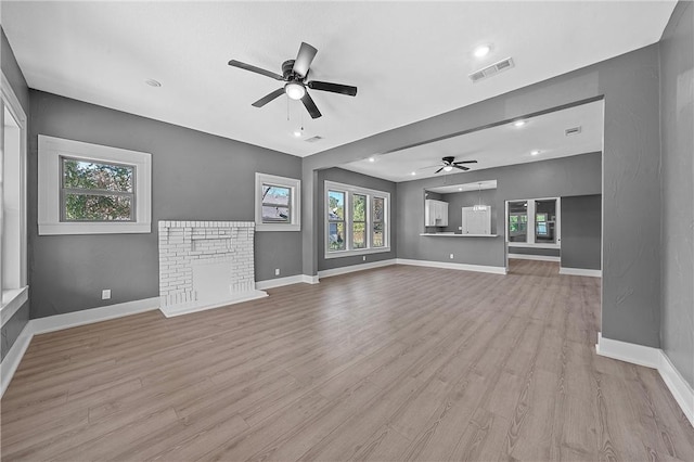 unfurnished living room featuring ceiling fan, a fireplace, and light hardwood / wood-style flooring