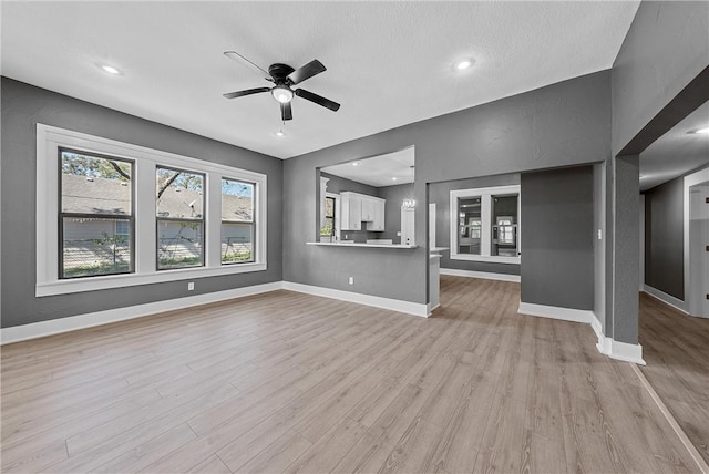 unfurnished living room featuring ceiling fan, a textured ceiling, and light wood-type flooring