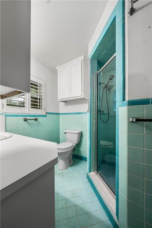 bathroom with tile walls, an enclosed shower, vanity, tile patterned floors, and toilet