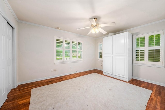 unfurnished bedroom with dark wood-type flooring, ceiling fan, crown molding, and a closet