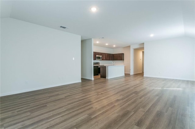 unfurnished living room with vaulted ceiling, wood finished floors, and recessed lighting