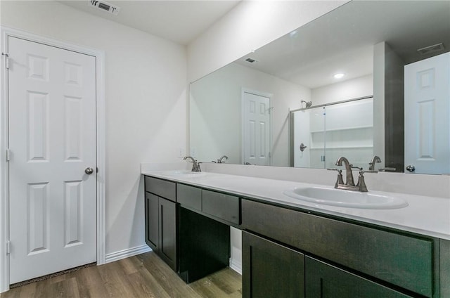 bathroom featuring double vanity, visible vents, a sink, and wood finished floors