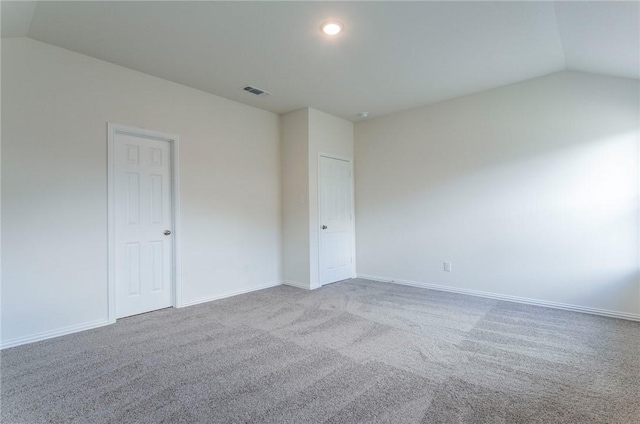 spare room with lofted ceiling, carpet floors, baseboards, and visible vents