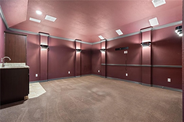 carpeted spare room featuring a textured ceiling, crown molding, sink, and lofted ceiling