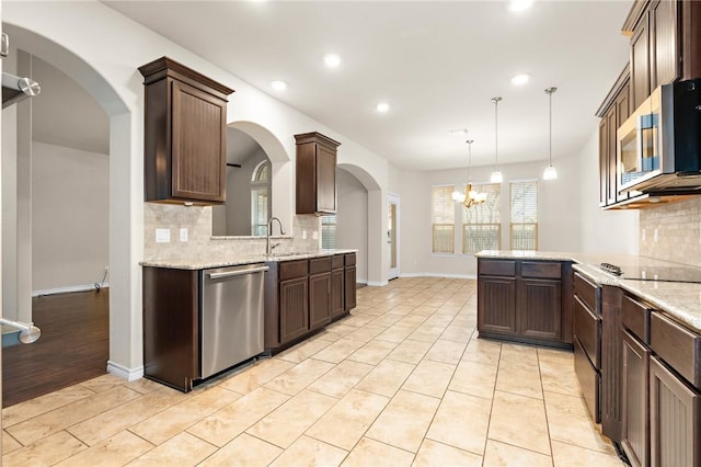 kitchen featuring hanging light fixtures, stainless steel appliances, kitchen peninsula, a chandelier, and decorative backsplash