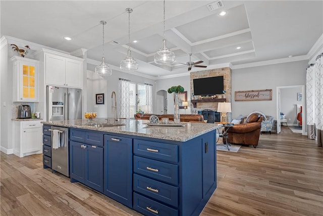 kitchen with white cabinets, stainless steel appliances, a kitchen island with sink, and sink