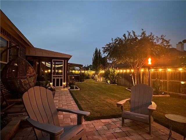 patio terrace at dusk featuring a lawn