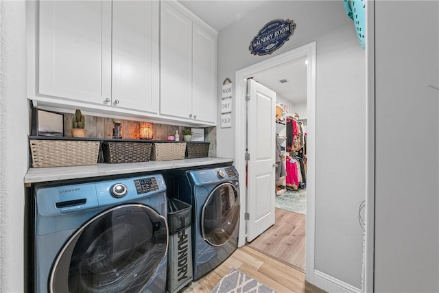 laundry area with washer and dryer, light hardwood / wood-style floors, and cabinets