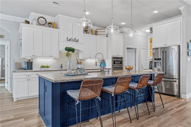 kitchen with stainless steel appliances, white cabinetry, and a kitchen island with sink