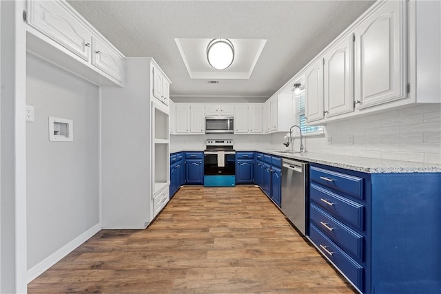 kitchen featuring light stone countertops, white cabinetry, stainless steel appliances, blue cabinets, and hardwood / wood-style flooring