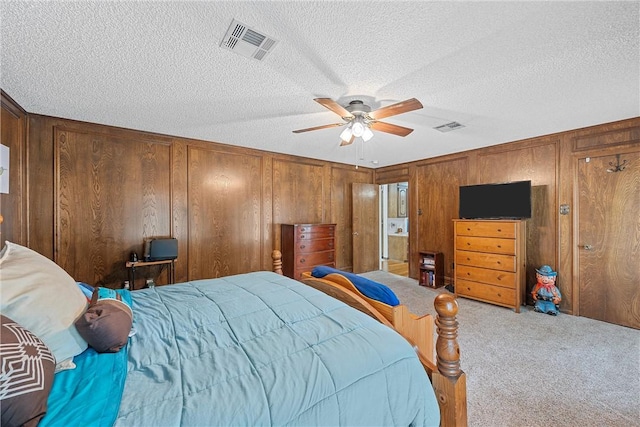 carpeted bedroom with ceiling fan, wood walls, and a textured ceiling