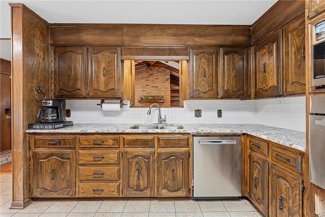 kitchen with light stone countertops, sink, a textured ceiling, light tile patterned floors, and appliances with stainless steel finishes