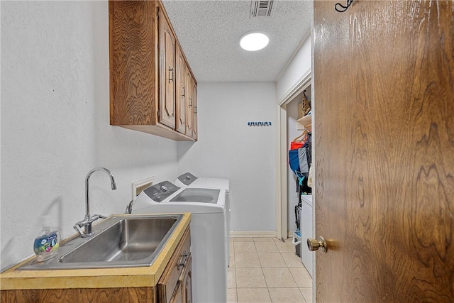 laundry room with cabinets, a textured ceiling, sink, light tile patterned floors, and independent washer and dryer