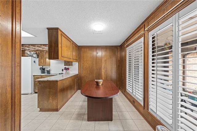 kitchen featuring light tile patterned floors, white refrigerator, a textured ceiling, and a kitchen island