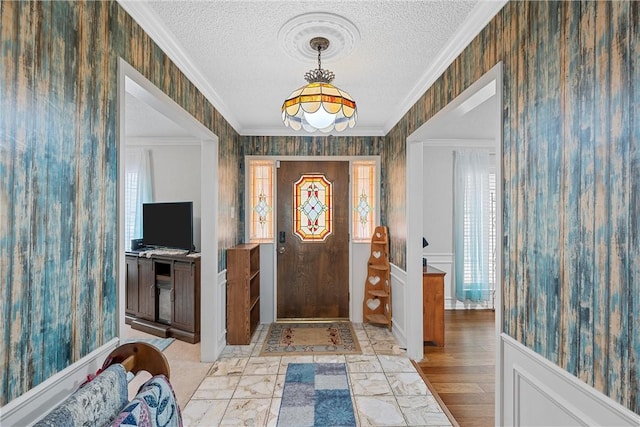 entryway with a wealth of natural light, light hardwood / wood-style flooring, a textured ceiling, and ornamental molding