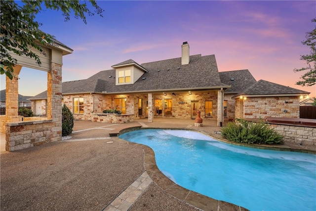 pool at dusk with a patio area