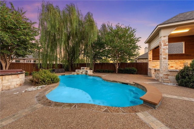 pool at dusk with pool water feature and a patio