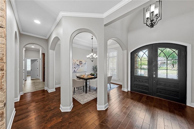 entrance foyer with dark hardwood / wood-style floors, ornamental molding, a chandelier, and french doors