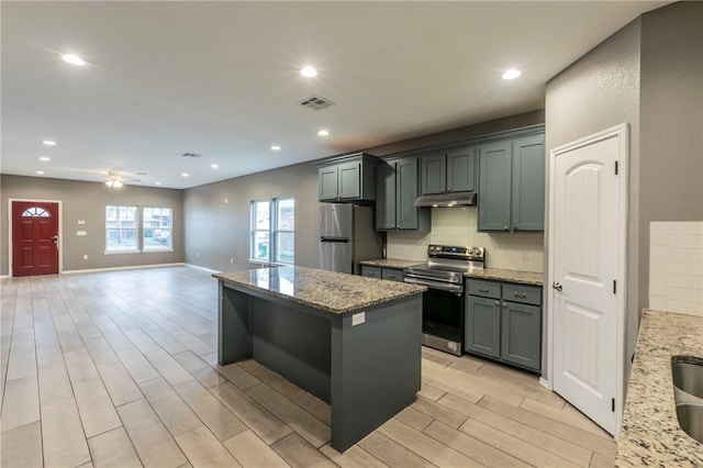 kitchen with light stone counters, a center island, stainless steel appliances, and light hardwood / wood-style floors