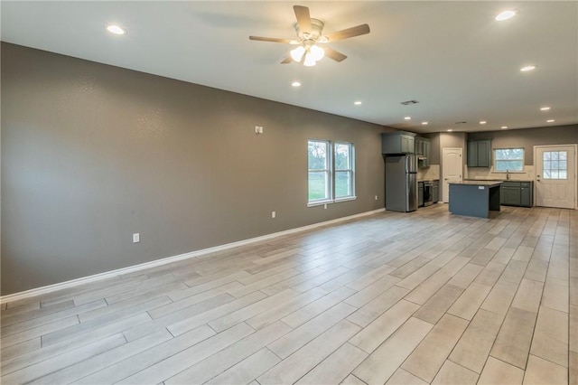 unfurnished living room with ceiling fan, light hardwood / wood-style flooring, and sink