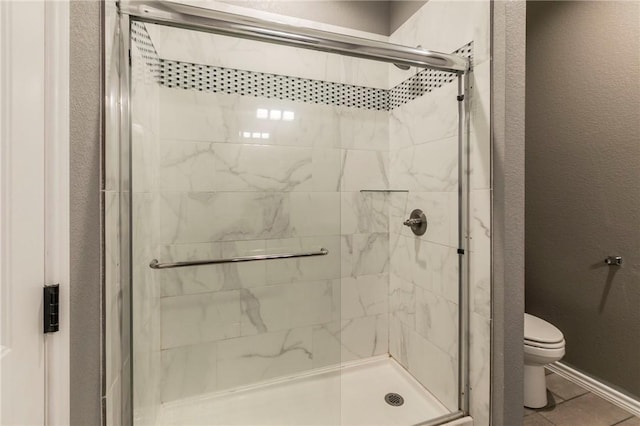 bathroom featuring tile patterned floors, toilet, and a shower with shower door