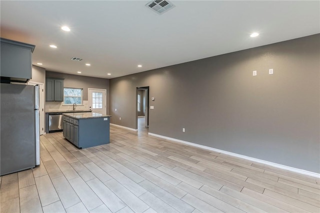 kitchen featuring gray cabinets, a kitchen island, light hardwood / wood-style floors, and stainless steel appliances