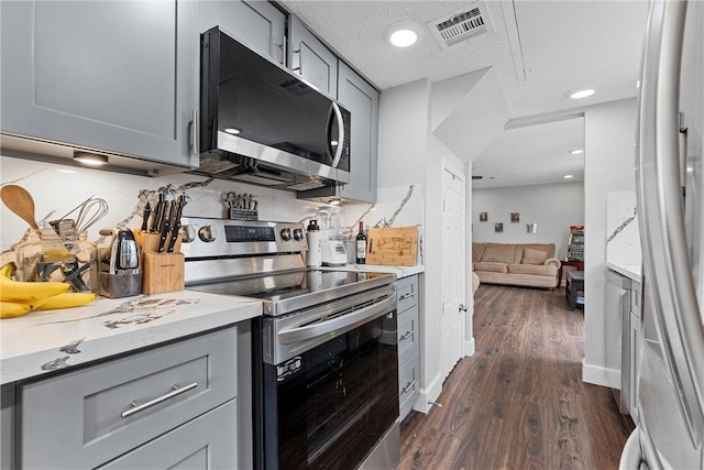 kitchen with stainless steel appliances, dark hardwood / wood-style floors, gray cabinets, and decorative backsplash