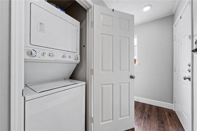 clothes washing area featuring stacked washer / dryer, dark hardwood / wood-style floors, and a textured ceiling