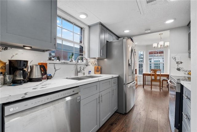 kitchen featuring dark wood-type flooring, sink, appliances with stainless steel finishes, gray cabinets, and pendant lighting