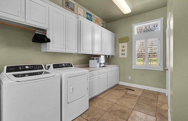 laundry room with stone tile floors, baseboards, washing machine and clothes dryer, cabinet space, and a sink