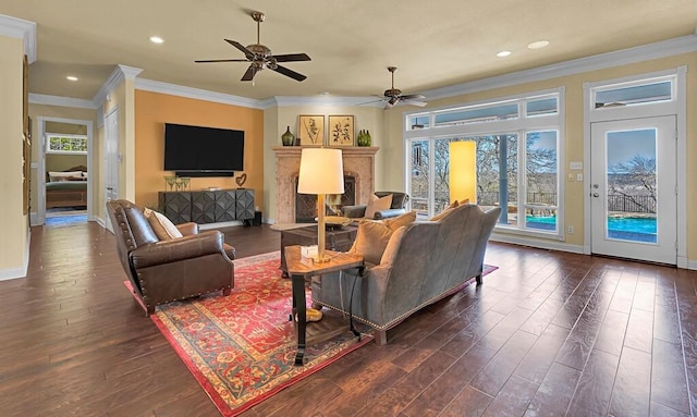 living area featuring baseboards, ornamental molding, recessed lighting, dark wood-style floors, and a ceiling fan