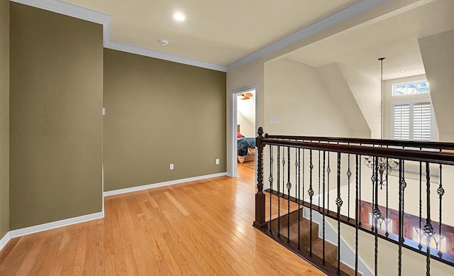 corridor with baseboards, light wood-style flooring, and ornamental molding