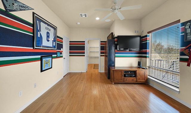 walk in closet with visible vents, a ceiling fan, and light wood finished floors