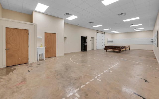 miscellaneous room featuring a paneled ceiling, visible vents, concrete flooring, and baseboards