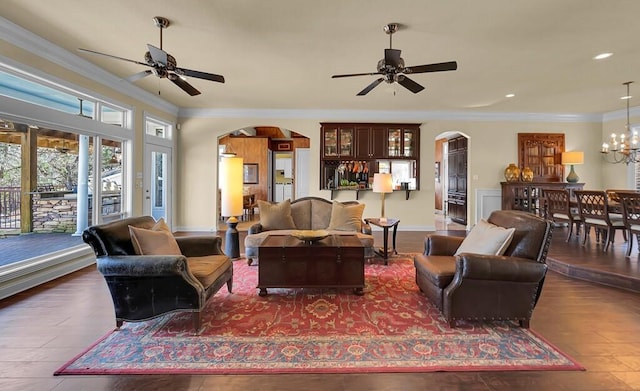 living room featuring arched walkways, ceiling fan with notable chandelier, and ornamental molding