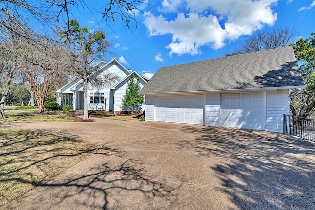 view of front of property with a detached garage, an outbuilding, and roof with shingles