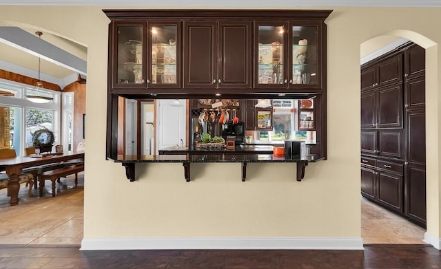 bar with arched walkways, hanging light fixtures, a dry bar, and baseboards