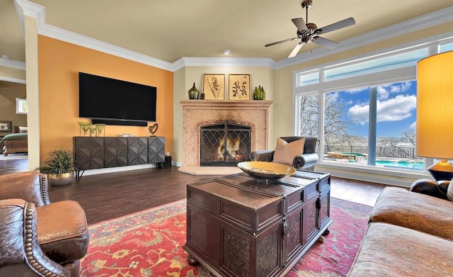 living room with a high end fireplace, crown molding, ceiling fan, and wood finished floors