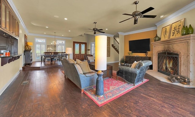 living room with ornamental molding, dark wood-style floors, a high end fireplace, and ceiling fan with notable chandelier