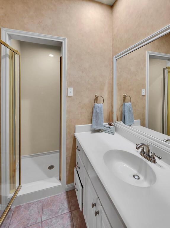 bathroom with tile patterned flooring, a shower stall, and vanity