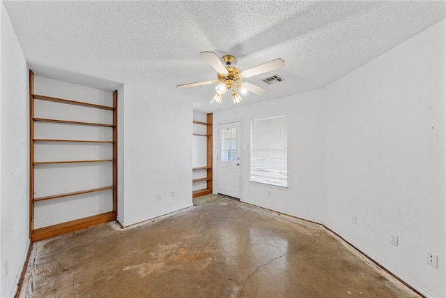 interior space featuring a textured ceiling, unfinished concrete flooring, visible vents, and a ceiling fan