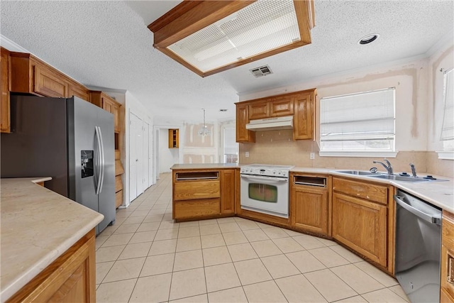 kitchen with under cabinet range hood, a sink, visible vents, light countertops, and appliances with stainless steel finishes