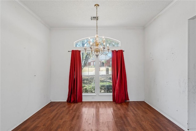 unfurnished room with a textured ceiling, plenty of natural light, wood finished floors, and visible vents