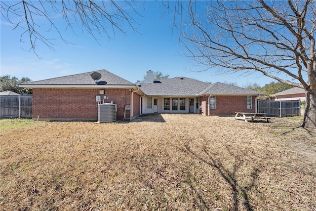 rear view of property featuring brick siding, fence, and central air condition unit