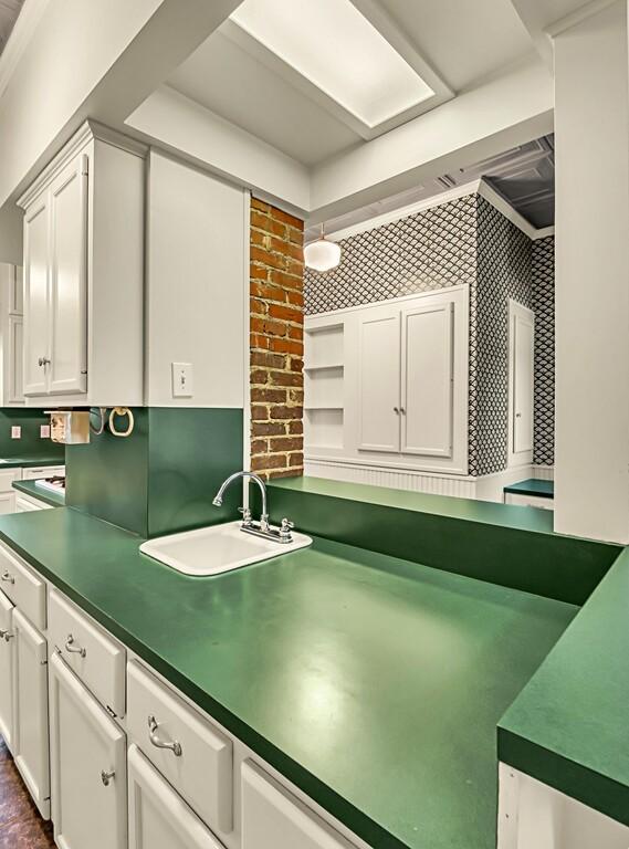 kitchen featuring white cabinets, backsplash, sink, and hanging light fixtures