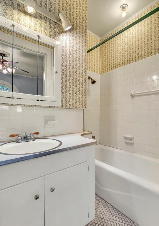 bathroom featuring ceiling fan, tiled shower / bath combo, tile patterned flooring, decorative backsplash, and vanity